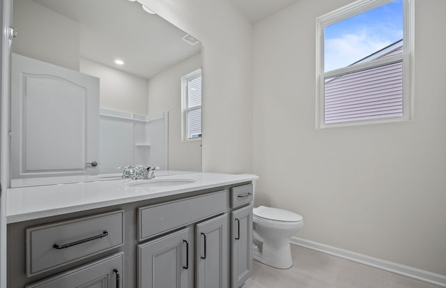 bathroom with baseboards, vanity, toilet, and a healthy amount of sunlight