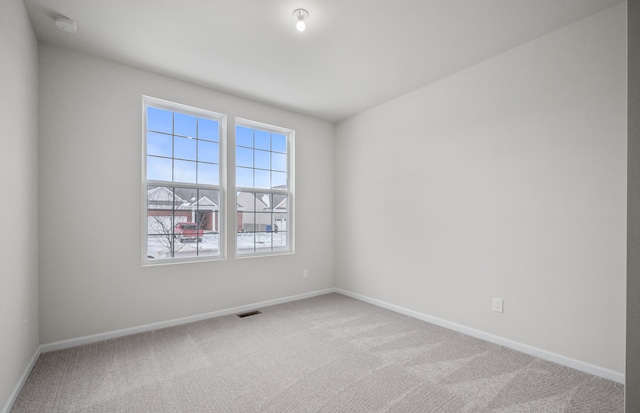 carpeted spare room with visible vents and baseboards