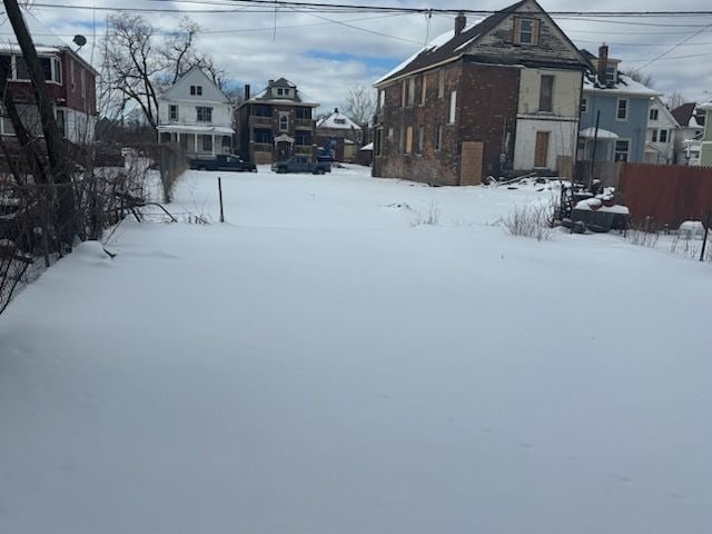 yard layered in snow featuring a residential view and fence