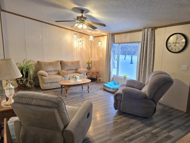 living room featuring ceiling fan, a textured ceiling, crown molding, and wood finished floors