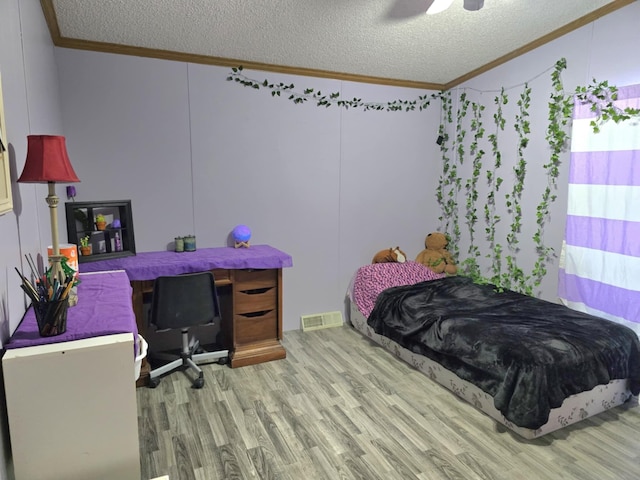 bedroom with a textured ceiling, wood finished floors, a ceiling fan, visible vents, and crown molding