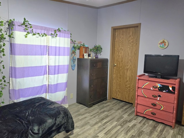 bedroom with crown molding and wood finished floors