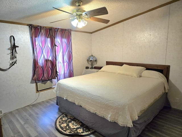 bedroom featuring a ceiling fan, ornamental molding, wood finished floors, a wall mounted air conditioner, and a textured ceiling