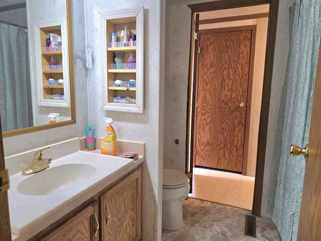 full bath with toilet, wallpapered walls, visible vents, and vanity