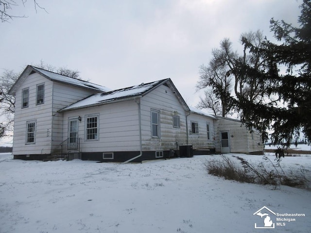 view of snowy exterior featuring a garage and cooling unit