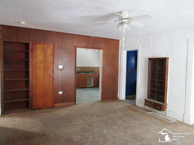 interior space with carpet, connected bathroom, and wooden walls