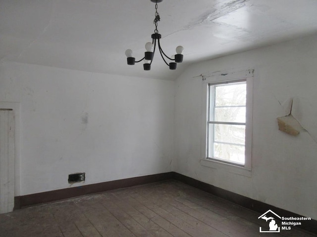 spare room featuring baseboards, vaulted ceiling, hardwood / wood-style floors, and an inviting chandelier