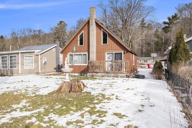 snow covered rear of property with a chimney