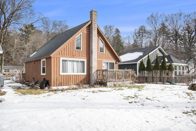 exterior space featuring a chimney, fence, and board and batten siding