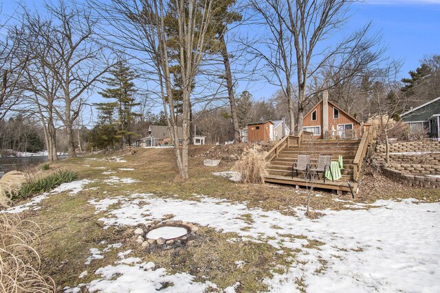 yard covered in snow featuring an outdoor structure, a wooden deck, and stairs