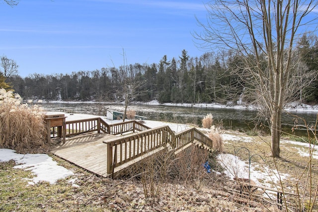 snow covered deck featuring a wooded view