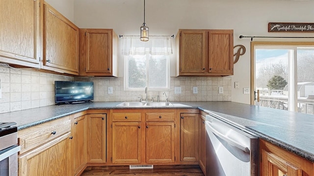 kitchen featuring brown cabinets, tasteful backsplash, hanging light fixtures, a sink, and dishwasher