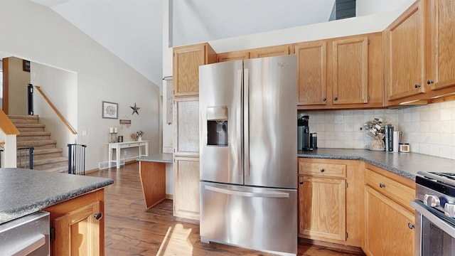 kitchen featuring stainless steel appliances, dark countertops, decorative backsplash, vaulted ceiling, and wood finished floors