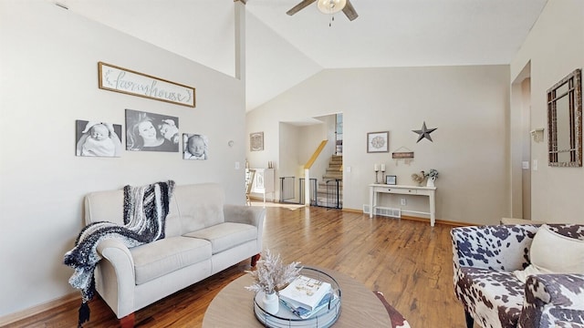 living room with ceiling fan, lofted ceiling, wood finished floors, visible vents, and stairs