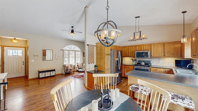 kitchen with dark wood finished floors, backsplash, an inviting chandelier, appliances with stainless steel finishes, and a sink