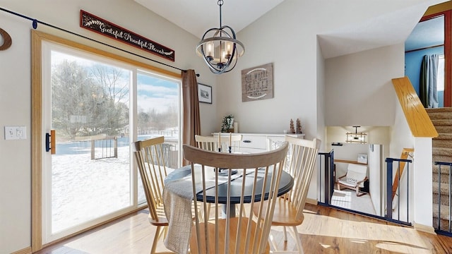 dining space featuring a notable chandelier, stairway, baseboards, and wood finished floors