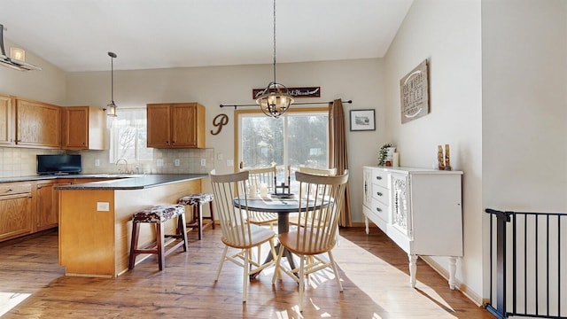 kitchen with a breakfast bar, tasteful backsplash, pendant lighting, and light wood-style flooring