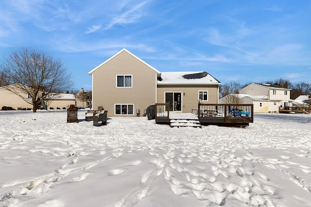 snow covered back of property with a wooden deck