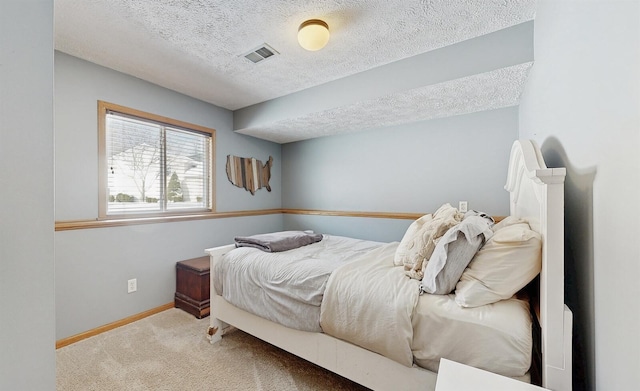 carpeted bedroom with visible vents, a textured ceiling, and baseboards