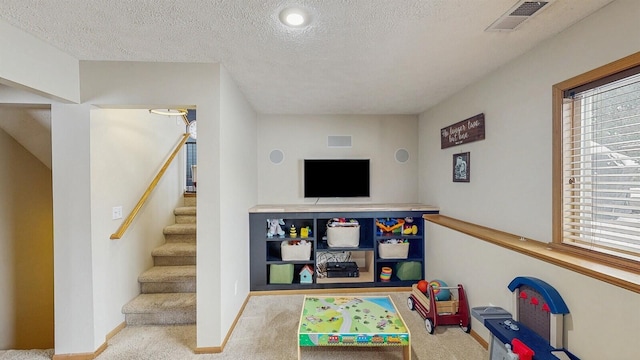 playroom with a textured ceiling, a wealth of natural light, carpet, and visible vents