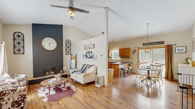 living room with lofted ceiling, a large fireplace, light wood-style flooring, and a ceiling fan