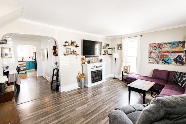 living area with arched walkways, dark wood-type flooring, a fireplace, baseboards, and ornamental molding