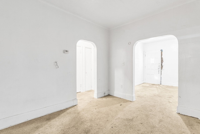 spare room with arched walkways, carpet flooring, and baseboards