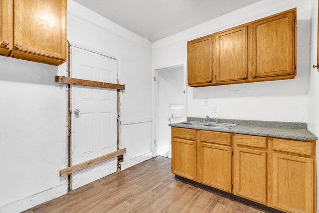 kitchen featuring a sink, light wood-style flooring, and brown cabinets