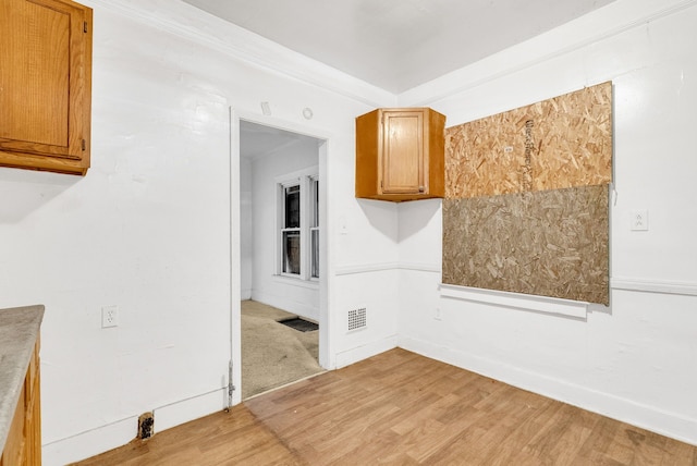 spare room featuring light wood-type flooring, visible vents, and baseboards