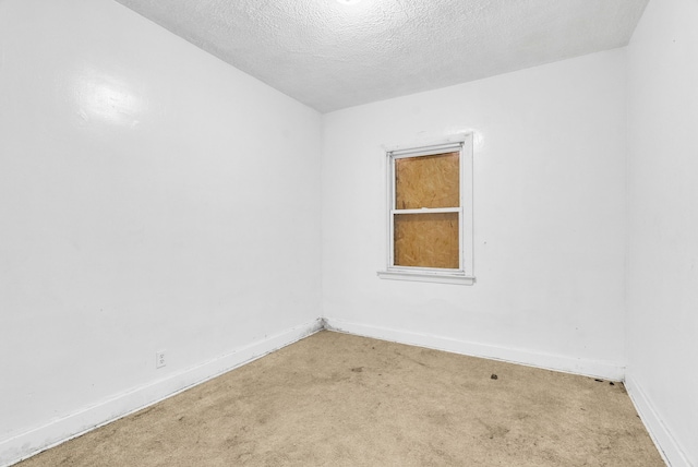 carpeted empty room featuring a textured ceiling and baseboards