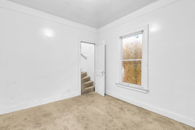 unfurnished room featuring carpet, baseboards, and stairs