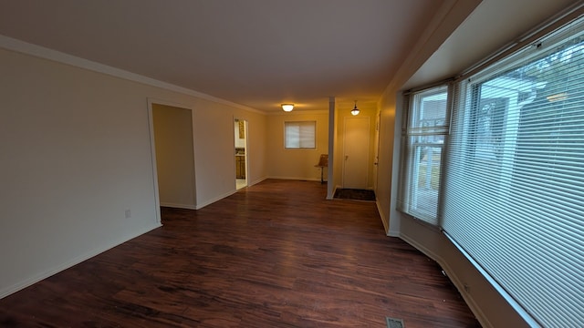 hallway featuring crown molding, dark wood finished floors, and baseboards