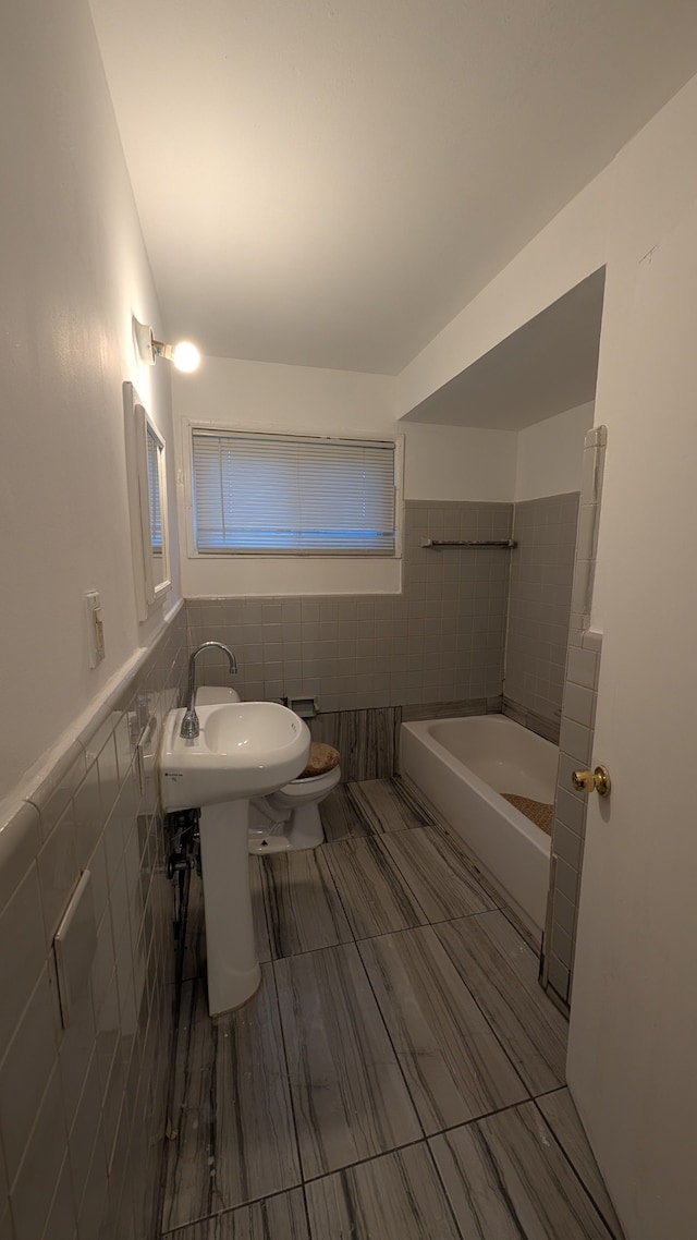 bathroom with toilet, tile walls, and wainscoting