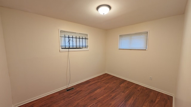 empty room with visible vents, baseboards, and dark wood finished floors