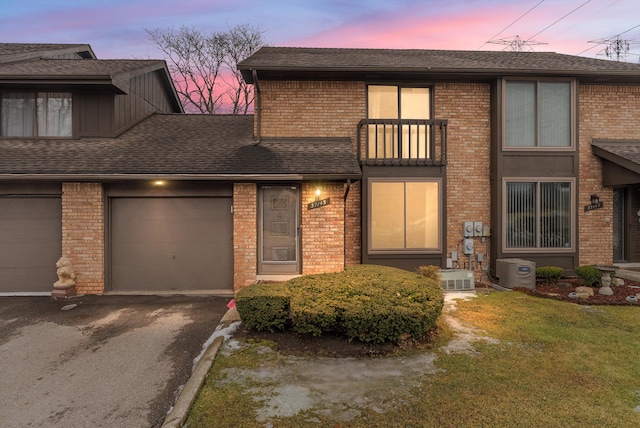 view of front facade with a shingled roof, brick siding, driveway, and an attached garage