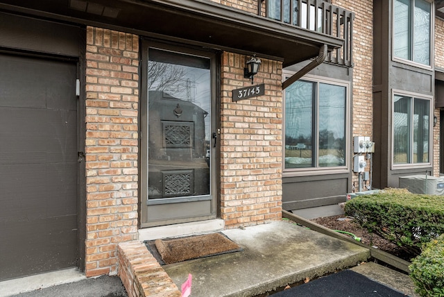 property entrance featuring brick siding and a balcony