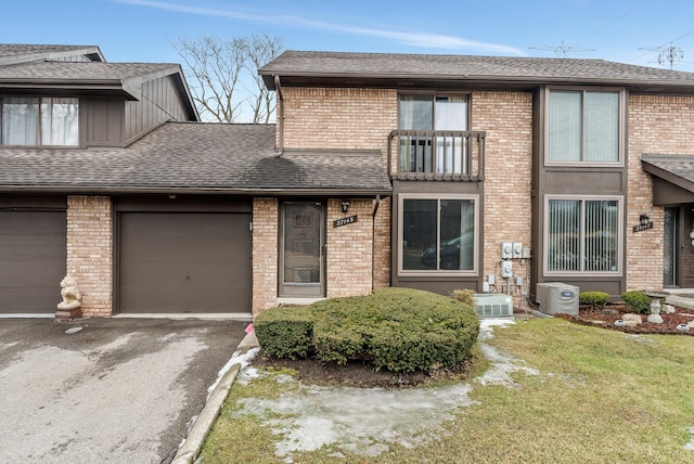 view of property featuring driveway, brick siding, roof with shingles, and an attached garage