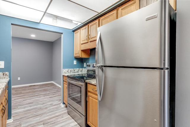 kitchen with appliances with stainless steel finishes, light wood-style floors, light stone counters, and light brown cabinetry