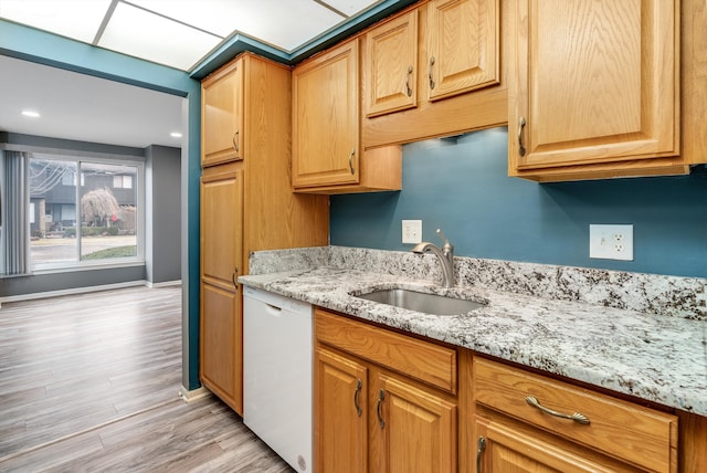 kitchen featuring white dishwasher, a sink, baseboards, light wood-style floors, and light stone countertops