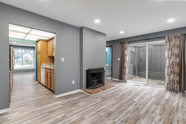 unfurnished living room featuring recessed lighting, baseboards, light wood-style floors, heating unit, and a wood stove