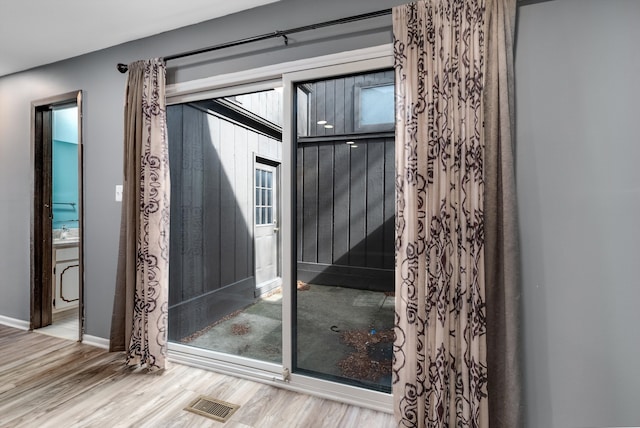 entryway with wood finished floors, visible vents, and baseboards
