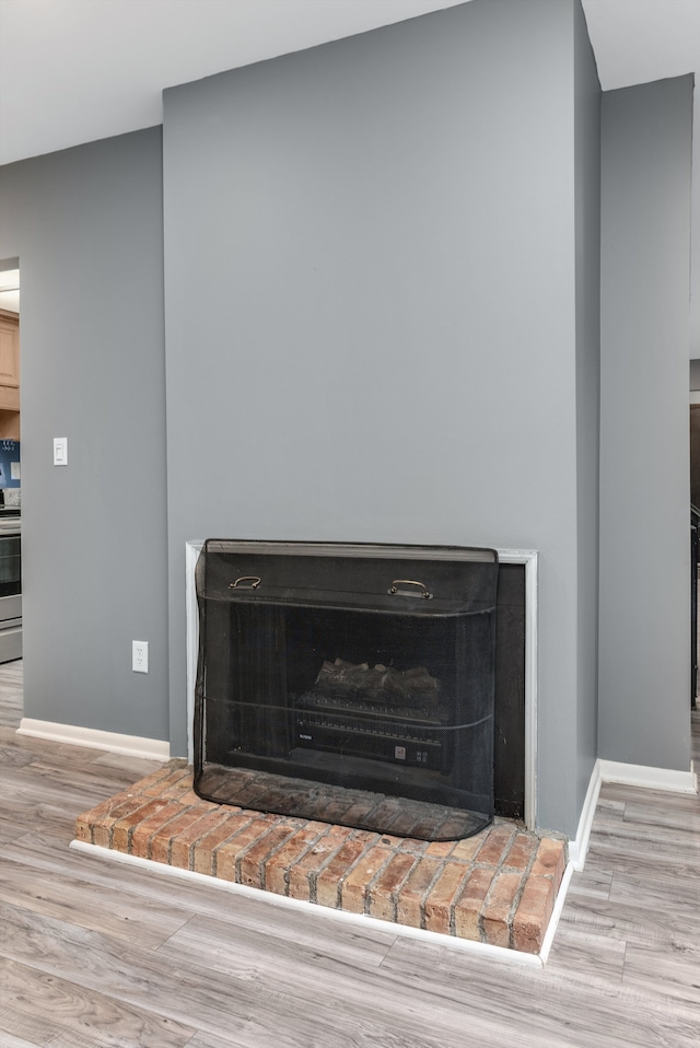 details featuring stainless steel electric range oven, a fireplace, baseboards, and wood finished floors