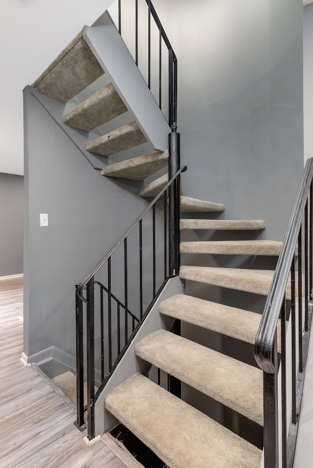 staircase with baseboards and wood finished floors