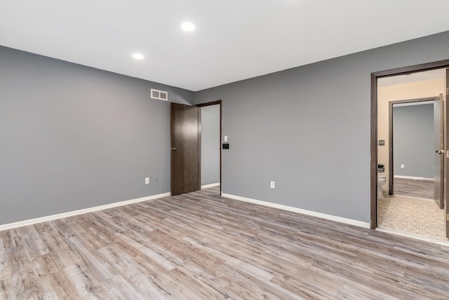 unfurnished room with light wood finished floors, visible vents, and baseboards