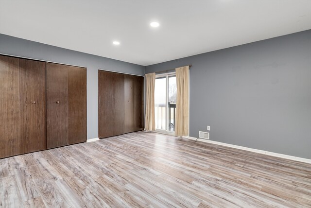 unfurnished bedroom featuring multiple closets, recessed lighting, visible vents, light wood-style flooring, and baseboards
