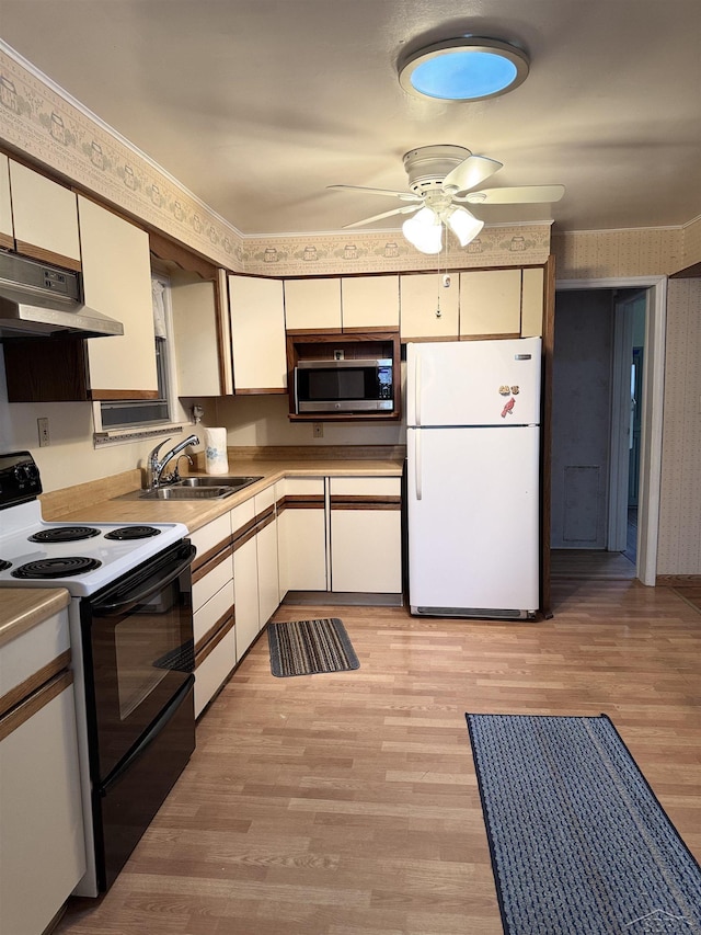 kitchen featuring electric stove, stainless steel microwave, freestanding refrigerator, under cabinet range hood, and a sink