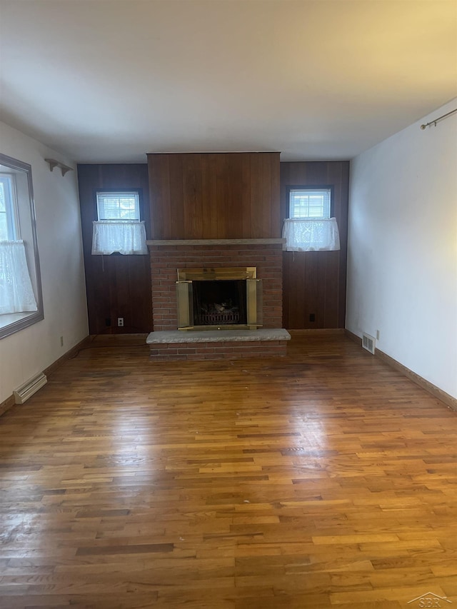 unfurnished living room featuring visible vents, a fireplace, baseboards, and wood finished floors