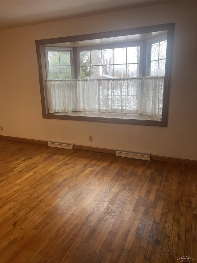 spare room with baseboards, visible vents, and wood finished floors