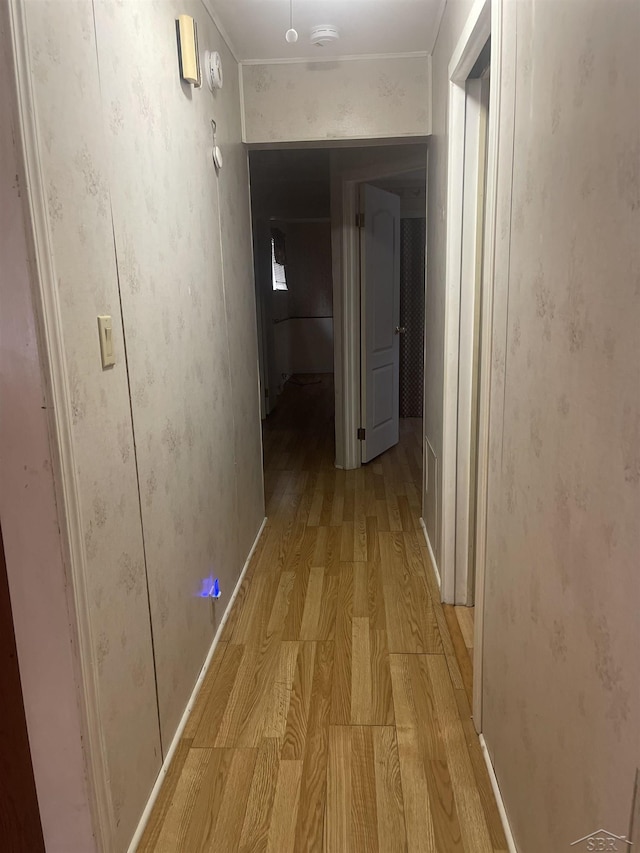 hallway featuring ornamental molding and light wood-type flooring