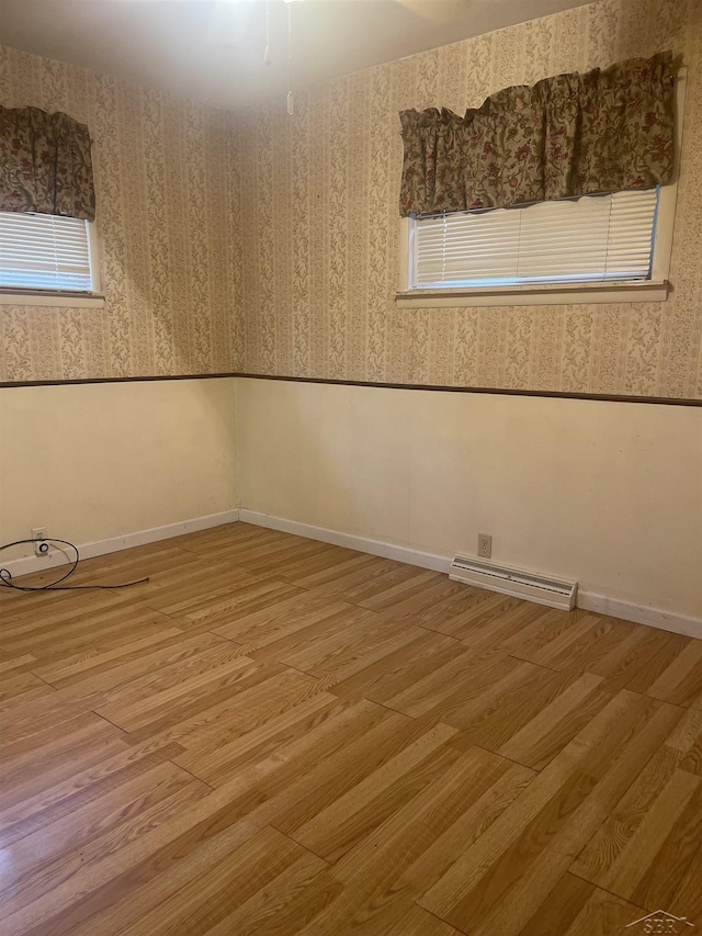 unfurnished room with wallpapered walls, baseboards, visible vents, and wood finished floors